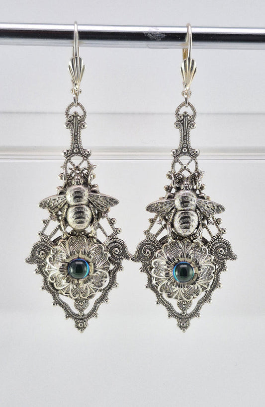 Sterling silver filled Victorian antique or reproduction work from original mold. The earrings feature an ornate silver filigree design embellished with a silver flower with iridescent light blue mini cabochon  &  a silver bee motif, all mounted on lever back earring hooks.