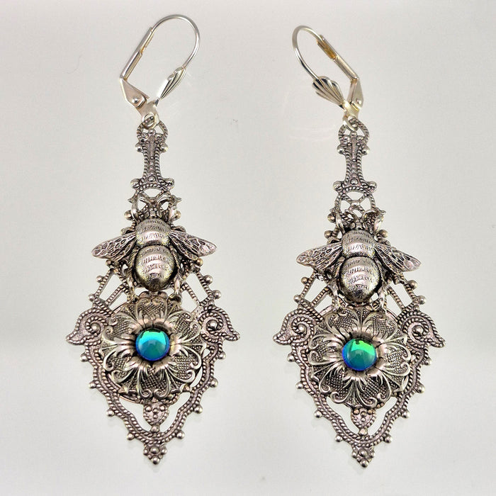 Sterling silver filled Victorian antique or reproduction work from original mold. The earrings feature an ornate silver filigree design embellished with a silver flower with iridescent light blue mini cabochon  &  a silver bee motif, all mounted on lever back earring hooks.