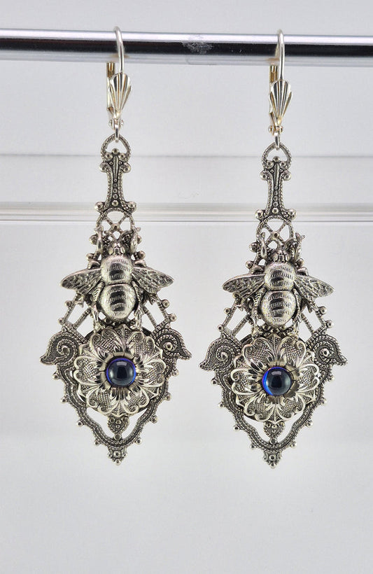 Sterling silver filled Victorian antique or reproduction work from original mold. The earrings feature an ornate silver filigree design embellished with a silver flower with iridescent royal blue mini cabochon  &  a silver bee motif, all mounted on lever back earring hooks.