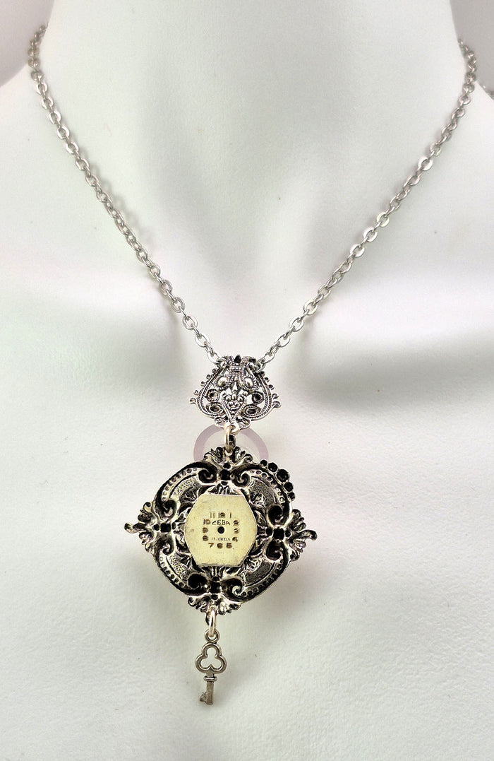 Antique Art Glass cabochon with varying colour display including amber and purple. The back side of the pendant is decorated with an antique watch face unique to each piece.