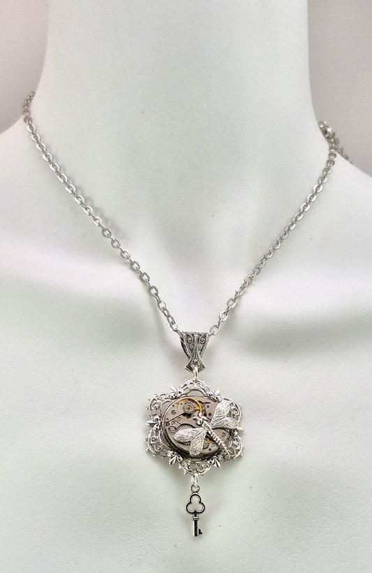 Sterling silver filled Victorian antique or reproduction work from original mold. The pendant features an ornate silver filigree design surrounding a vintage clockworks embellished with a dragonfly.