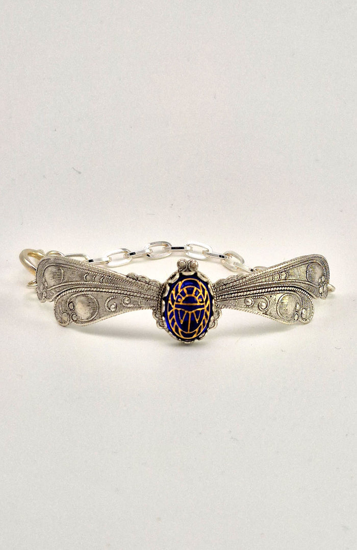 Sterling silver filled Victorian antique or reproduction work from original mold. The bracelet features a silver dragonfly wing design surrounding a central bright lapis  coloured antique Art Glass cabochon with an etched scarab design.