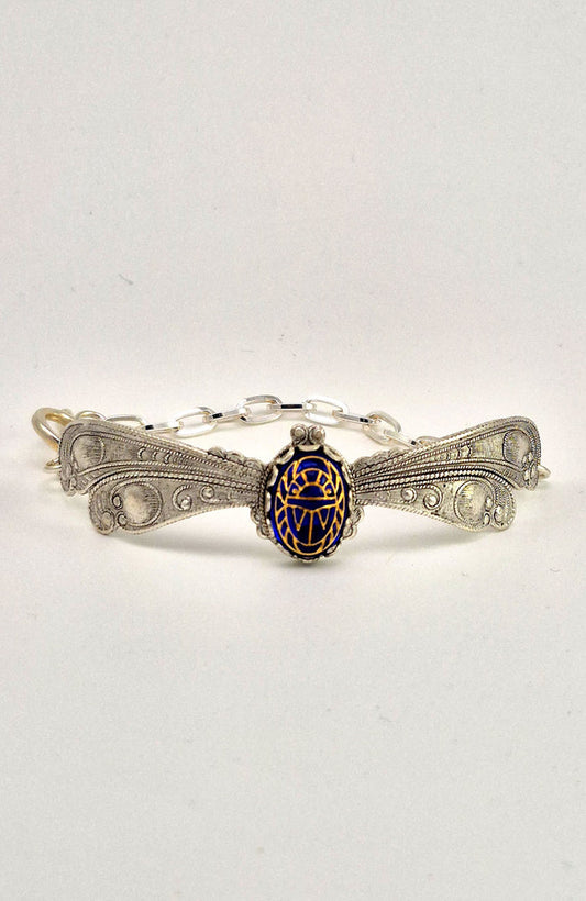Sterling silver filled Victorian antique or reproduction work from original mold. The bracelet features a silver dragonfly wing design surrounding a central bright lapis  coloured antique Art Glass cabochon with an etched scarab design.