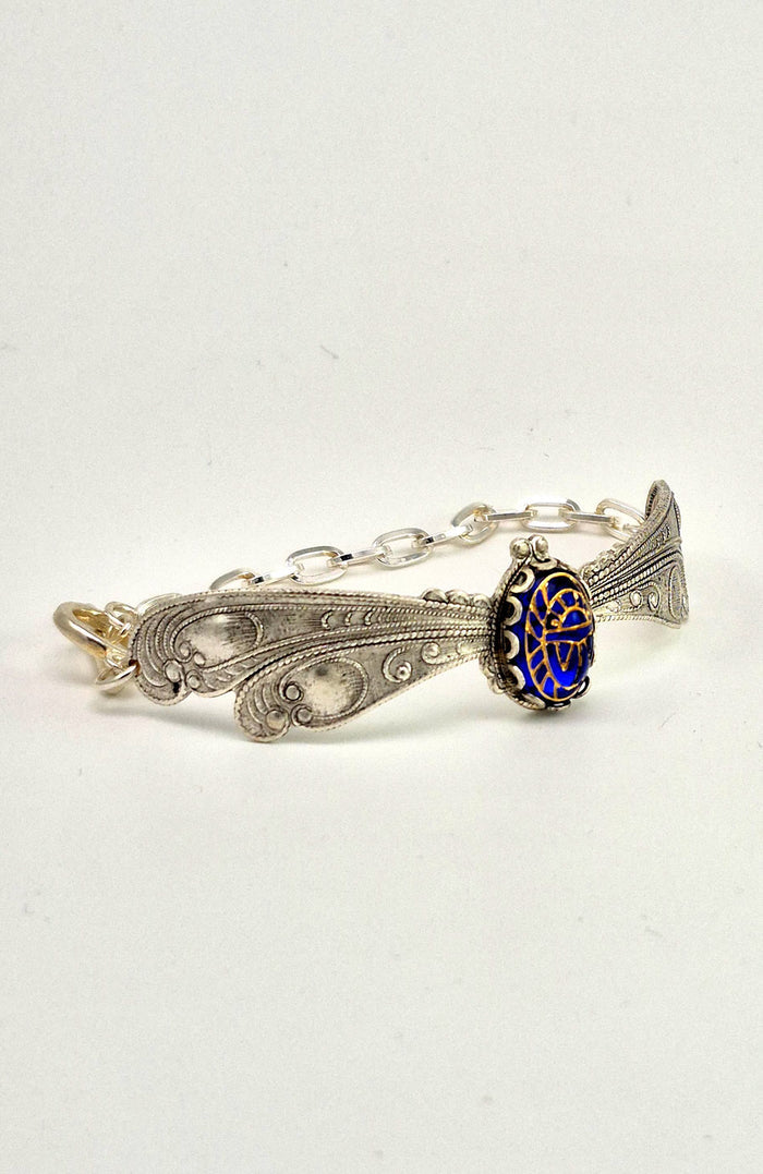 Sterling silver filled Victorian antique or reproduction work from original mold. The bracelet features a silver dragonfly wing design surrounding a central bright lapis  coloured antique Art Glass cabochon with an etched scarab design.