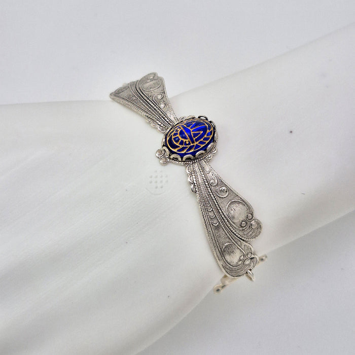 Sterling silver filled Victorian antique or reproduction work from original mold shown on a mannequin wrist. The bracelet features a silver dragonfly wing design surrounding a central bright lapis coloured antique Art Glass cabochon with an etched scarab design.