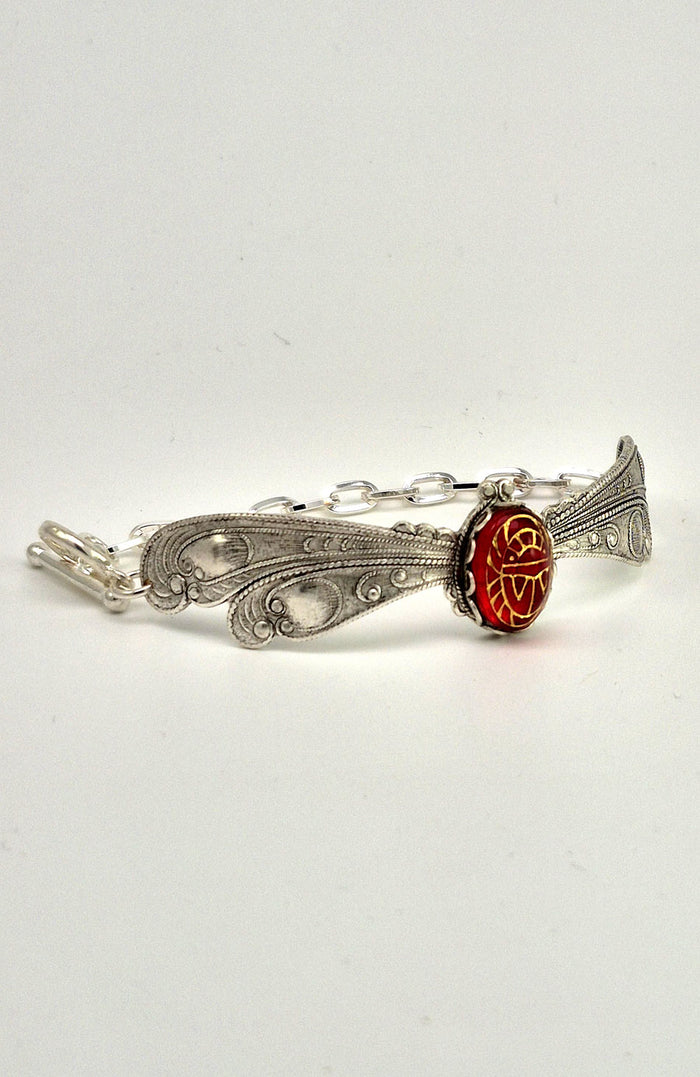 Sterling silver filled Victorian antique or reproduction work from original mold. The bracelet features a silver dragonfly wing design surrounding a central bright ruby coloured antique Art Glass cabochon with an etched scarab design.