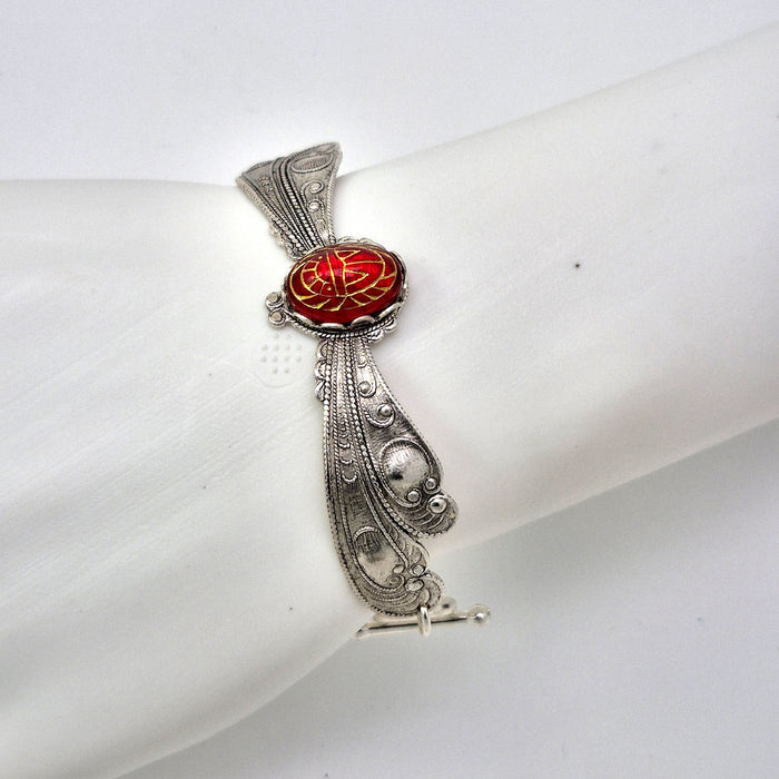 Sterling silver filled Victorian antique or reproduction work from original mold shown on a mannequin wrist. The bracelet features a silver dragonfly wing design surrounding a central bright ruby coloured antique Art Glass cabochon with an etched scarab design.