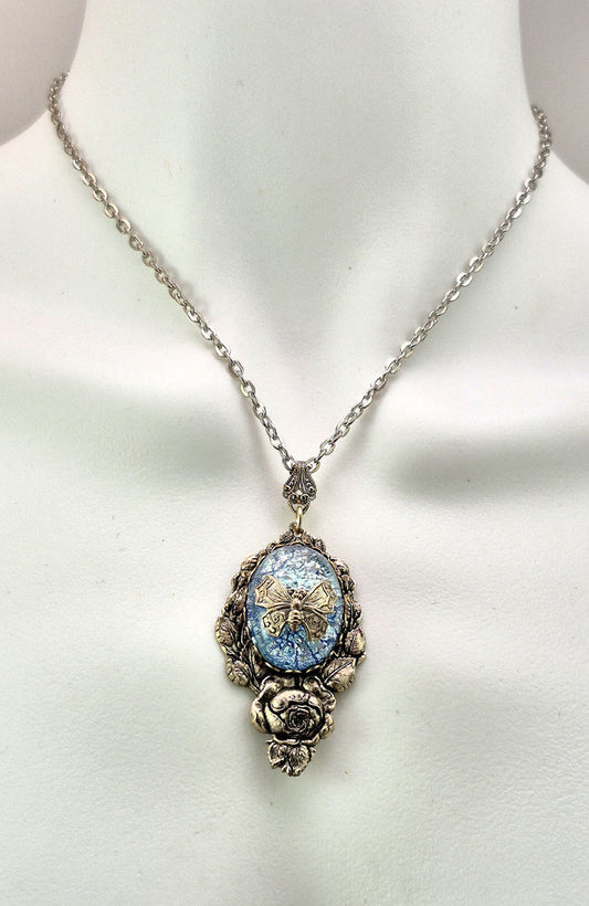 Sterling silver filled Victorian antique or reproduction work from original mold. The pendant features a silver floral design surrounding a central bright ice blue iridescent antique Art Glass cabochon with a butterfly motif.