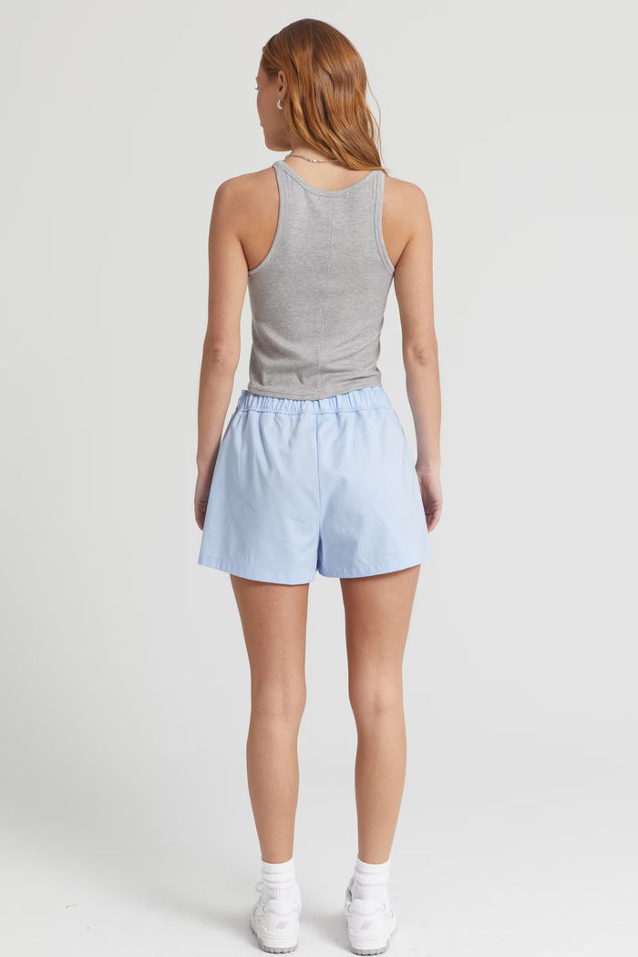 Person wearing a gray tank top and light blue shorts on a white background