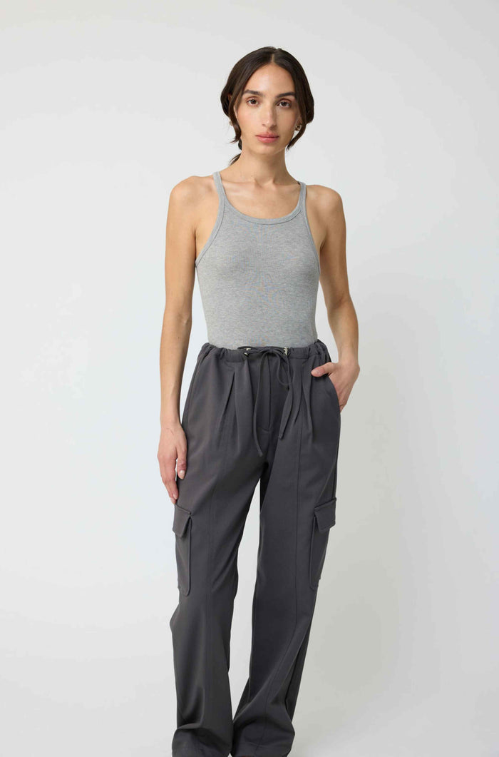Woman wearing a gray tank top and dark gray pants on a white background