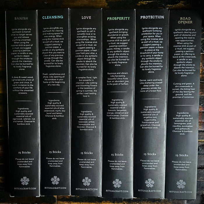 Set of six black boxes of incense labeled with different categories on a wooden surface.