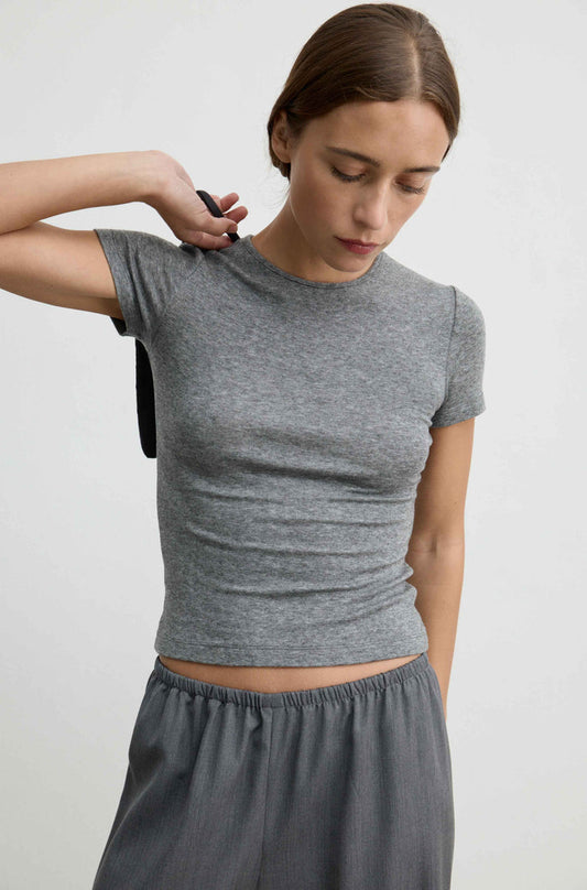 A woman wearing a fitted heather gray short-sleeve crop top and matching gray pants, photographed against a plain light gray studio background.
